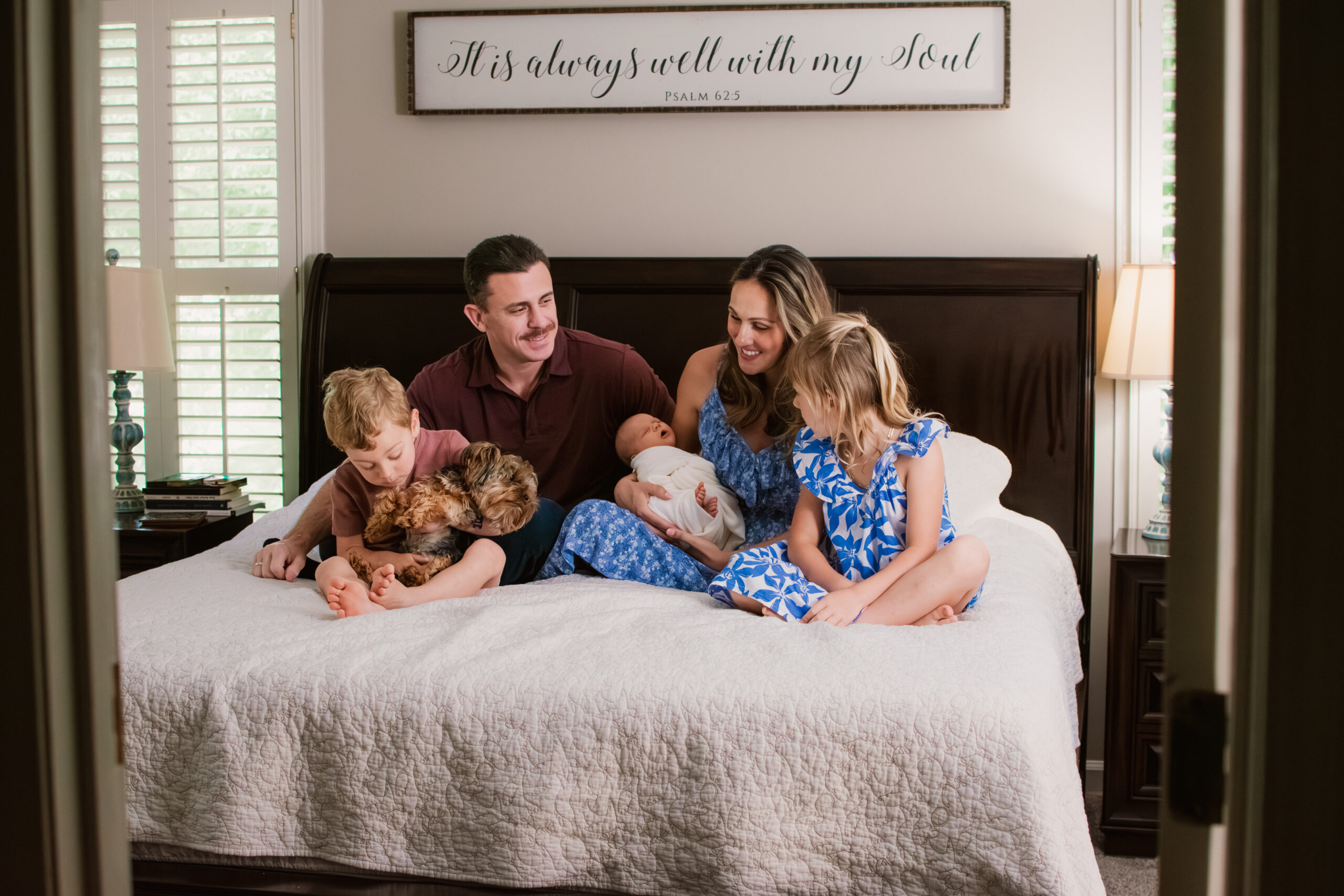 Family snuggles together on bed during in-home newborn session in Lilburn, Georgia.