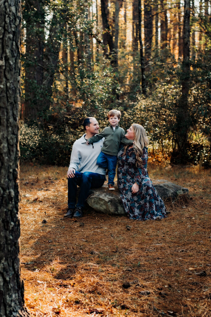 Family sits on rocks in botanical gardens in Loganville, Georgia during photo session