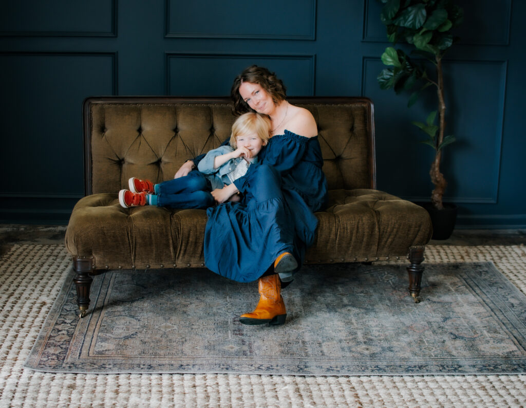 Mom and son snuggle on green couch during motherhood photoshoot