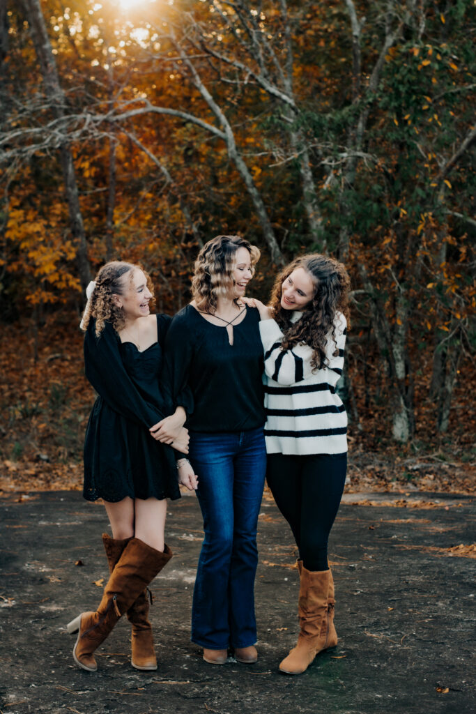 Mom and daughters hold hands and laugh during family photo session
