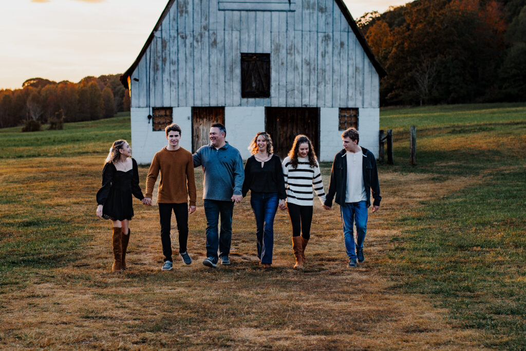 Family walks hand in hand as sun sets behind the barn at Vaughters Farm.