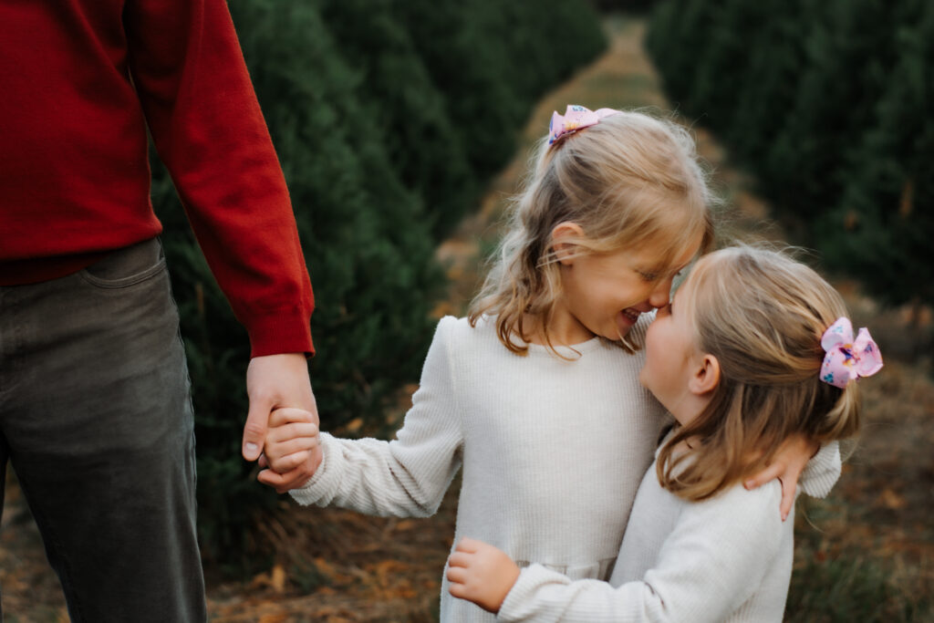 Sisters hugging at a Christmas tree farm