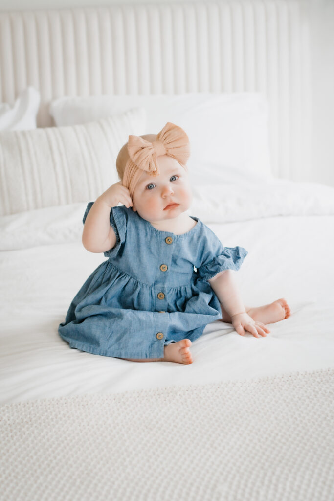 Little girl sits on white bed