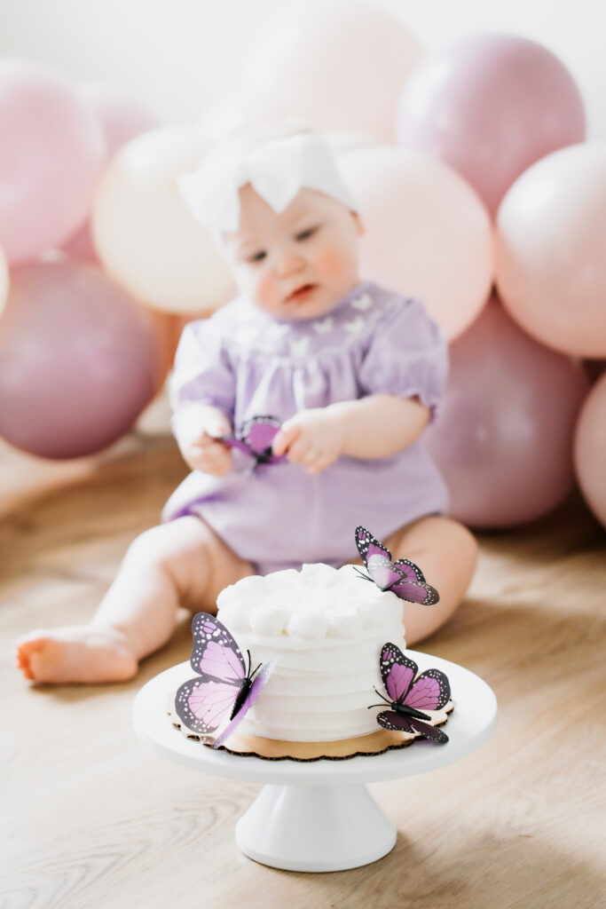 Little girl and cake with purple butterfly decorations
