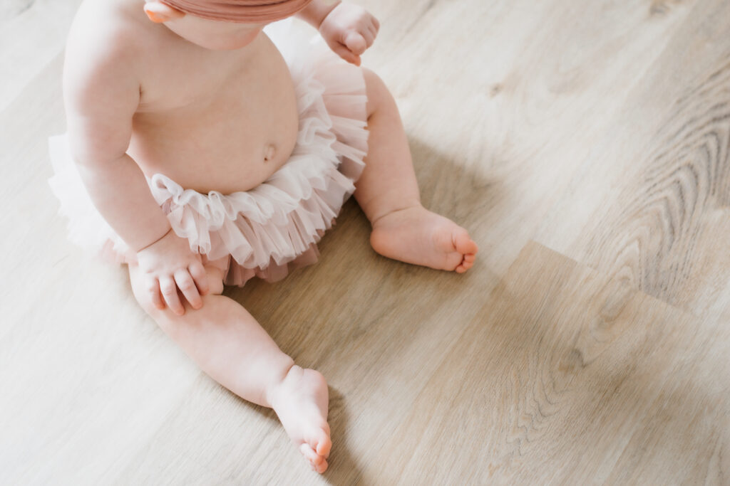 Little girl sits in pink tutu i photography studio