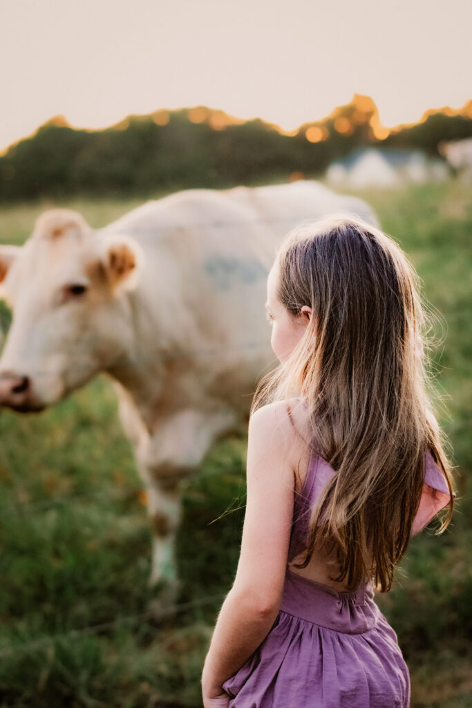 Girls and cow stand in field