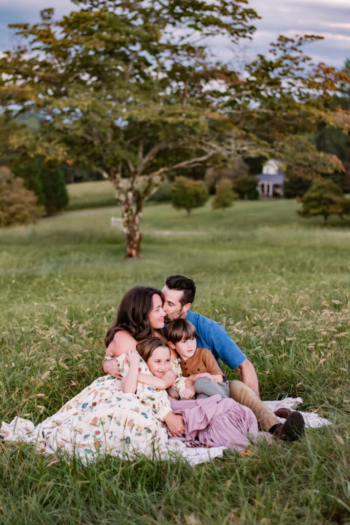 Family on a quilt in tall grass on a farm