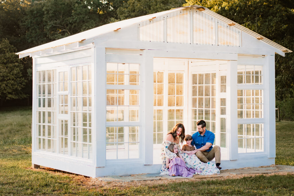 Family in glass greenhouse during golden hour
