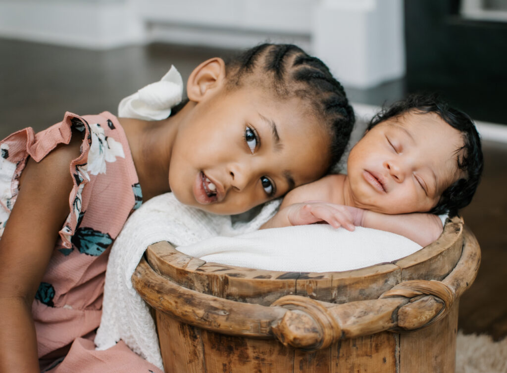Toddler and her new baby brother posing