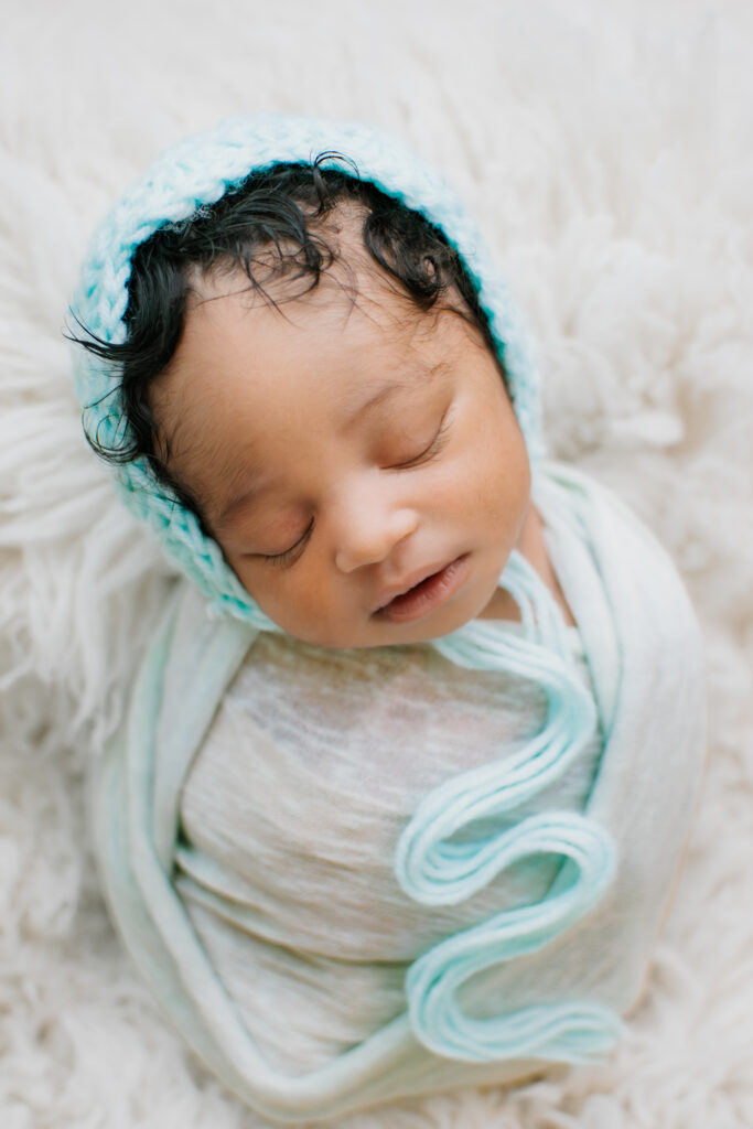 teal swaddle and bonnet on a newborn