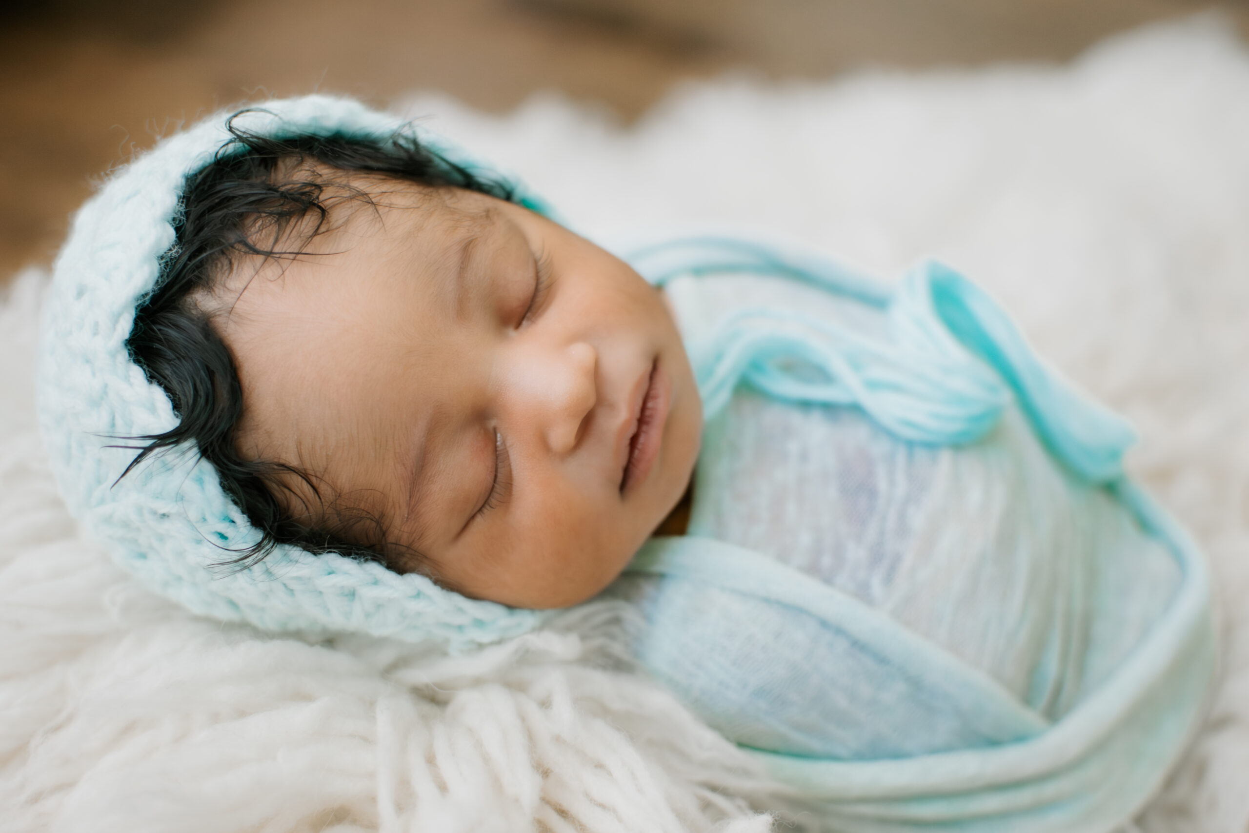 Baby swaddled in teal wrap and bonnet