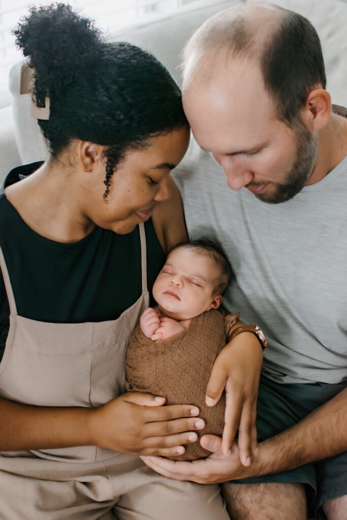 Mom and dad gaze down at their daughter during an in-home newborn session in the family home in Norcross, Georgia.