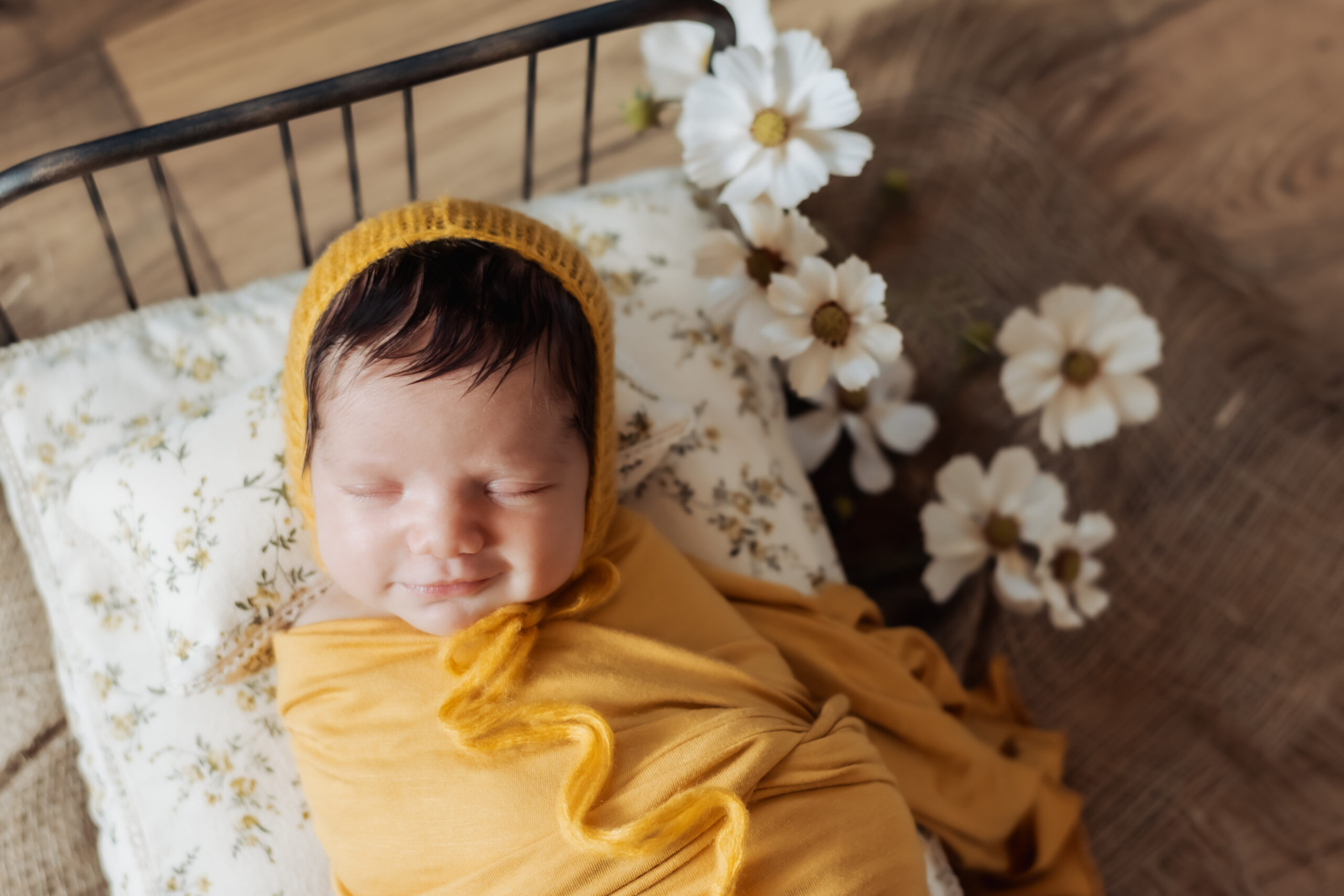 newborn smiles wrapped in yellow swaddle during in-home newborn session