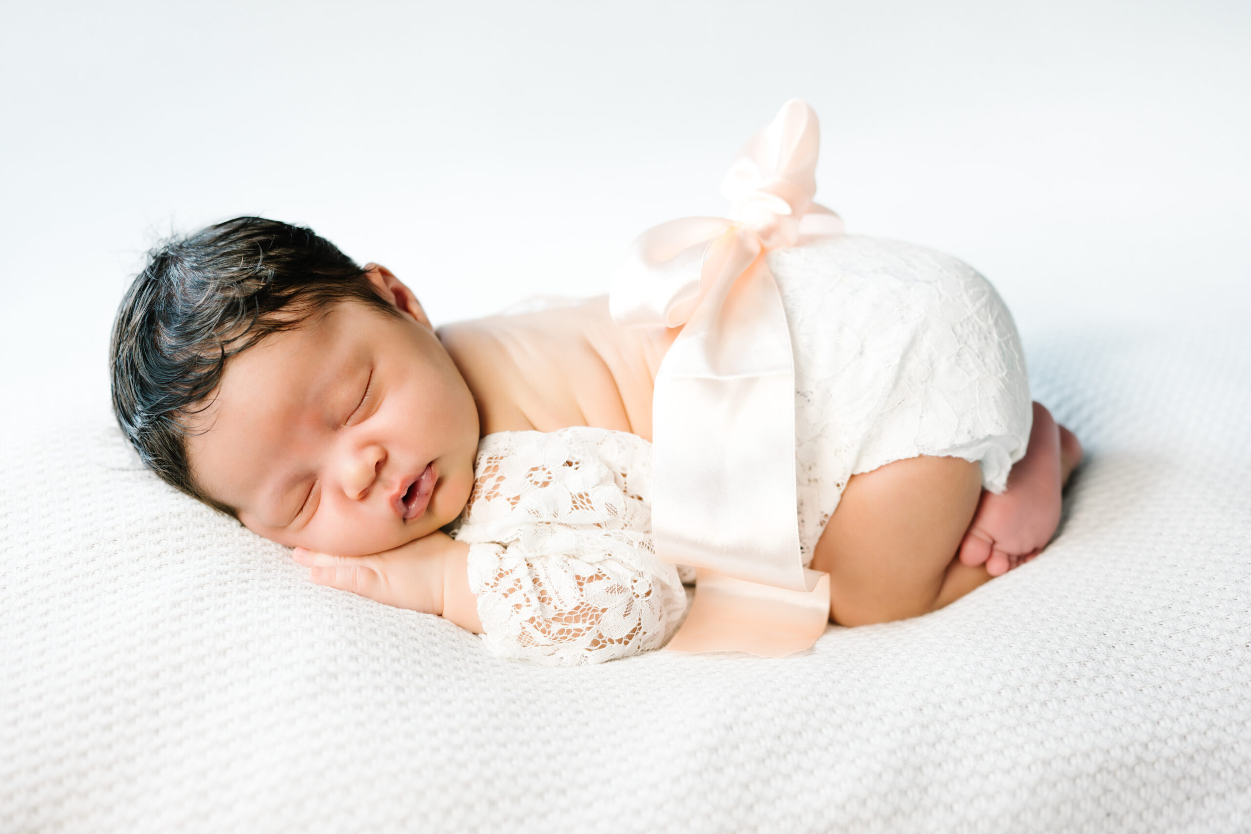 newborn in lace outfit sleeping in bum up pose during in-home newborn session