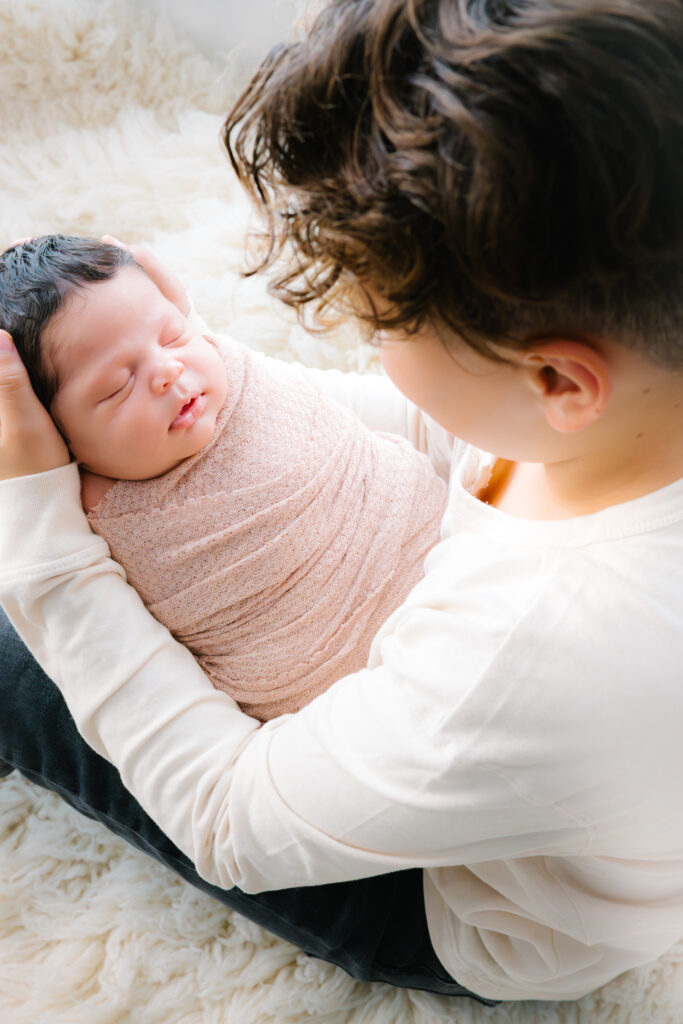 Brother holds his younger sister in his lap during an in-home newborn session.