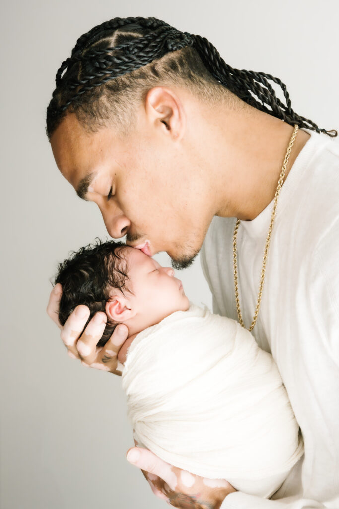Dad kissing son's forehead during an in-home newborn photo session.