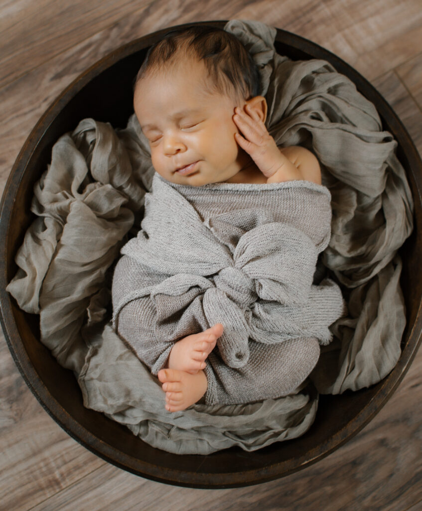 newborn photo of a baby girl nested in a bowl with fabric