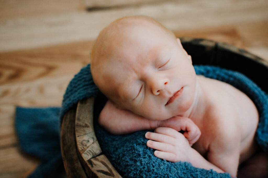 Newborn resting posed in a bucket during in-home photo session