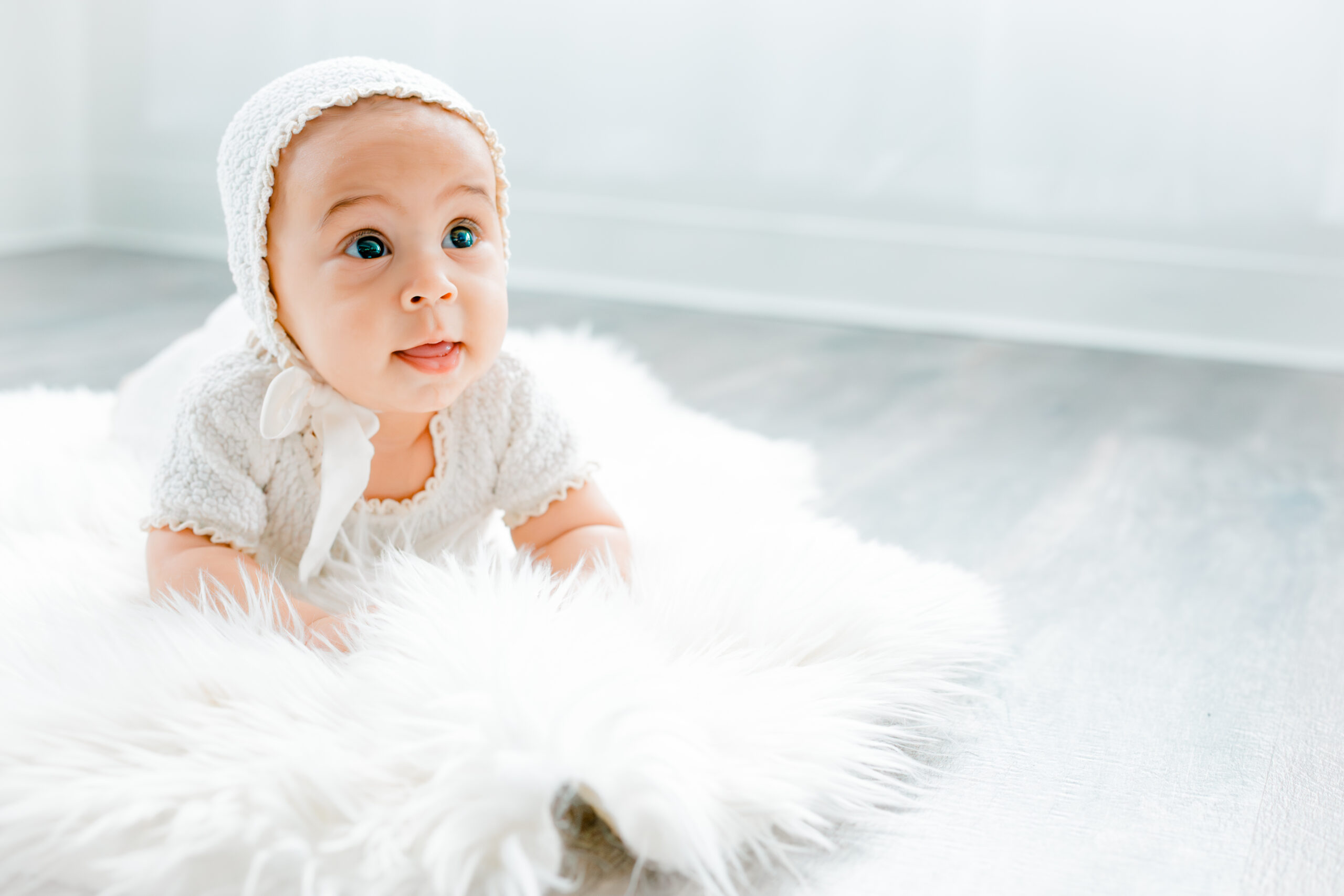 six month milestone session baby on white rug