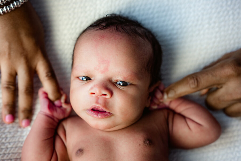 newborn photo of baby boy holding mom and dad's fingers, eyes wide open