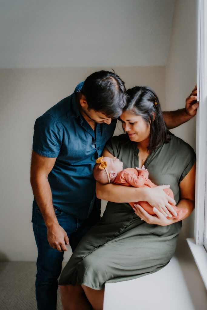 Dad leans over mom in a window during Atlanta newborn session