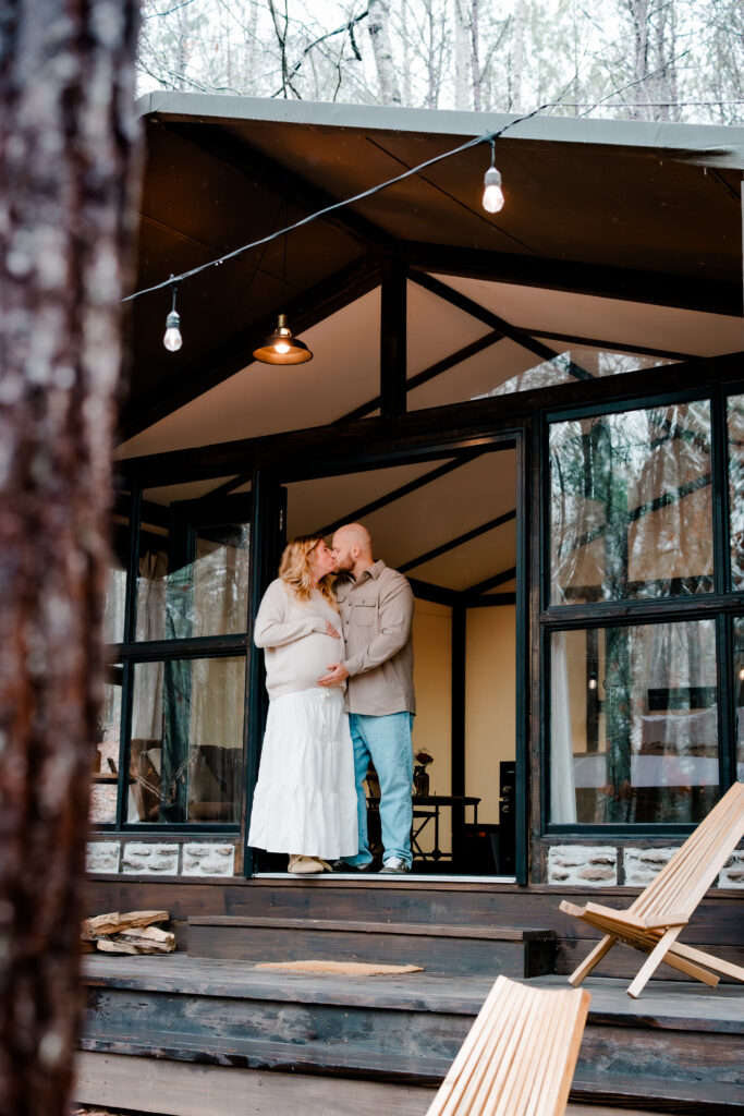 Couple kisses in doorway during maternity session