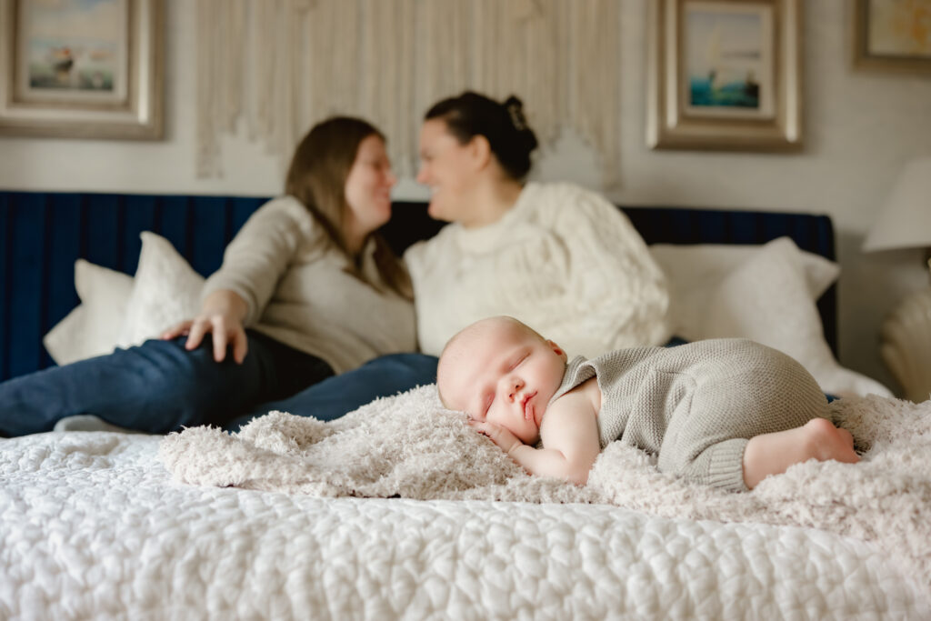 Lilburn newborn photo session with moms on bed and baby sleeping at the foot