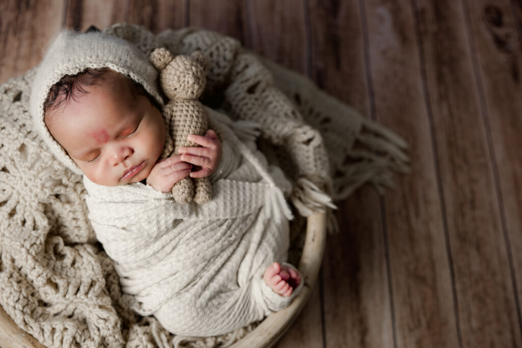 Posed newborn photo of baby in bowl with teddy bear