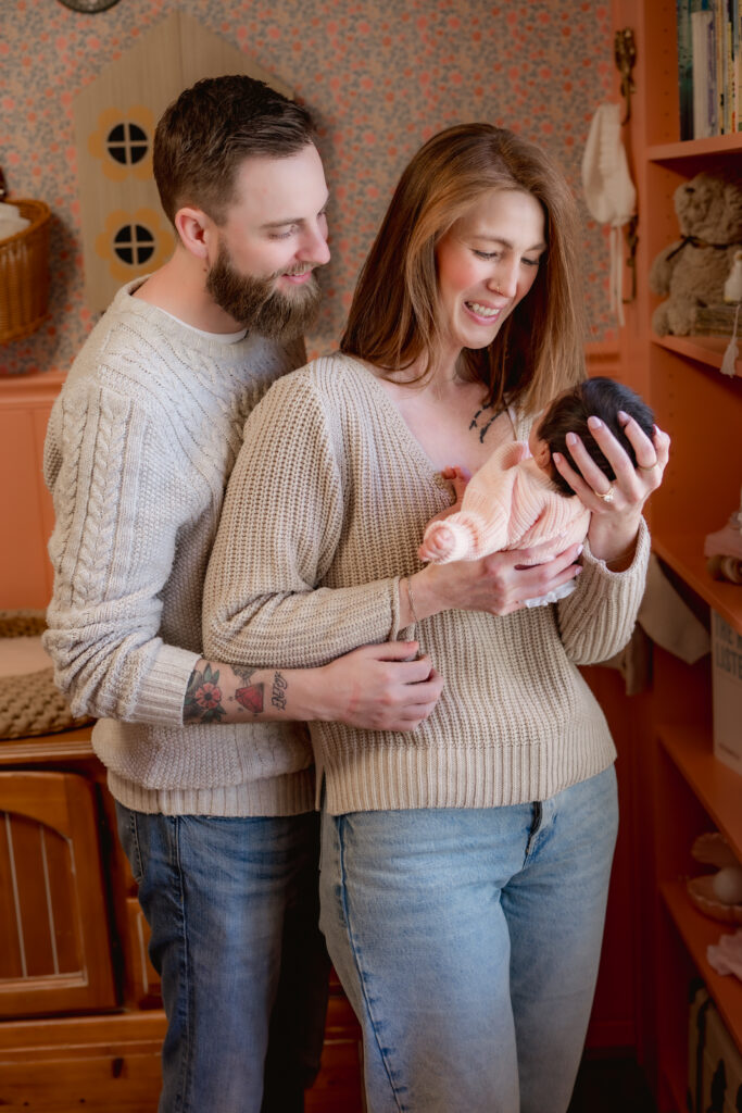 Mom and dad smile down at newborn baby in mom's arms