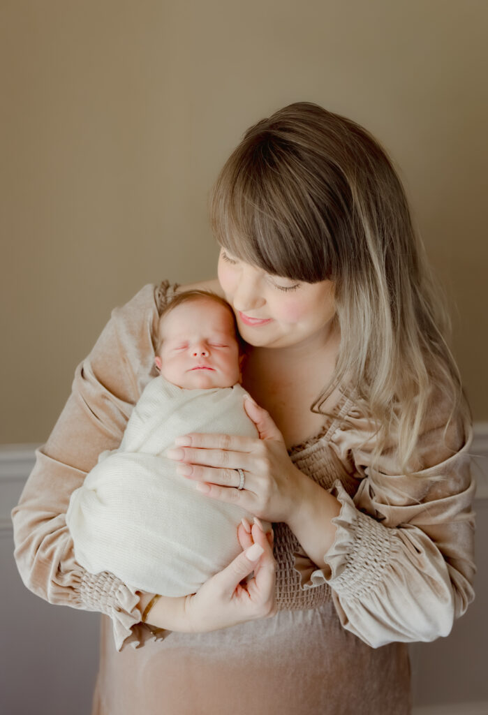 Mom holding newborn baby during in-home photo session