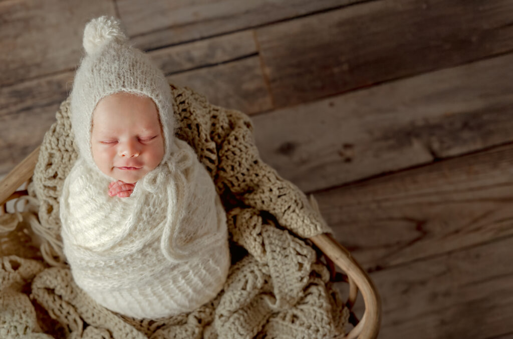 Smiling newborn posed in mohair wrap and basket