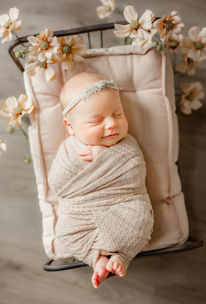 Newborn posed in pink fabric on small aron bed