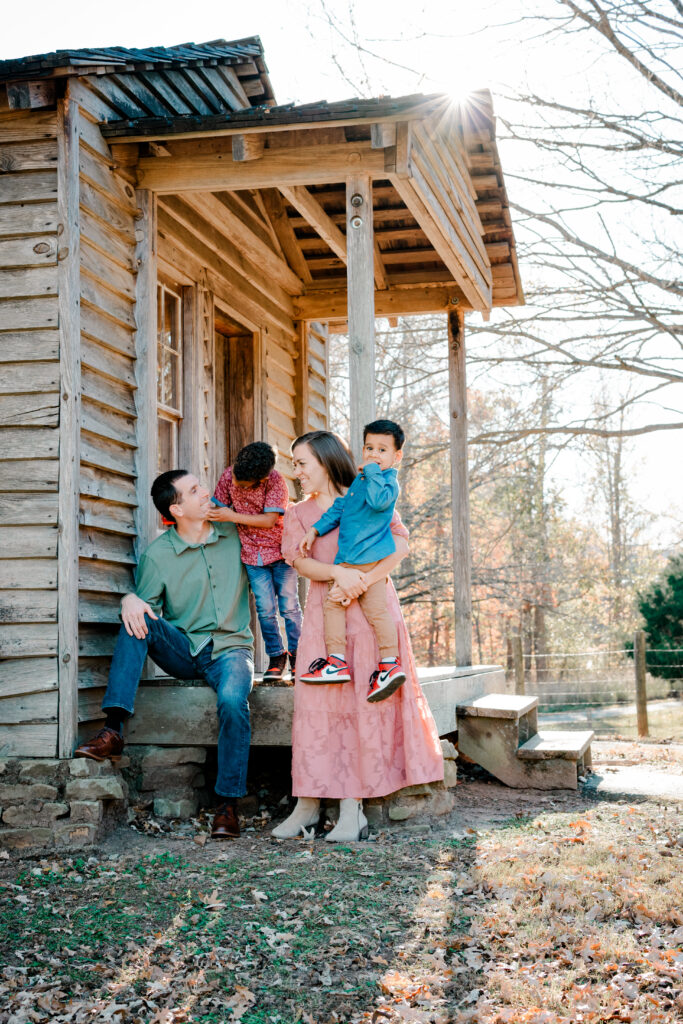 Family in spring colors on old rustic porch during Atlanta family photo session at McDaniel Farm Park