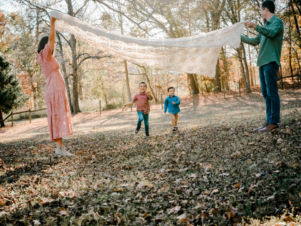 Kids running under a blanket during a photo session at an Atlanta park