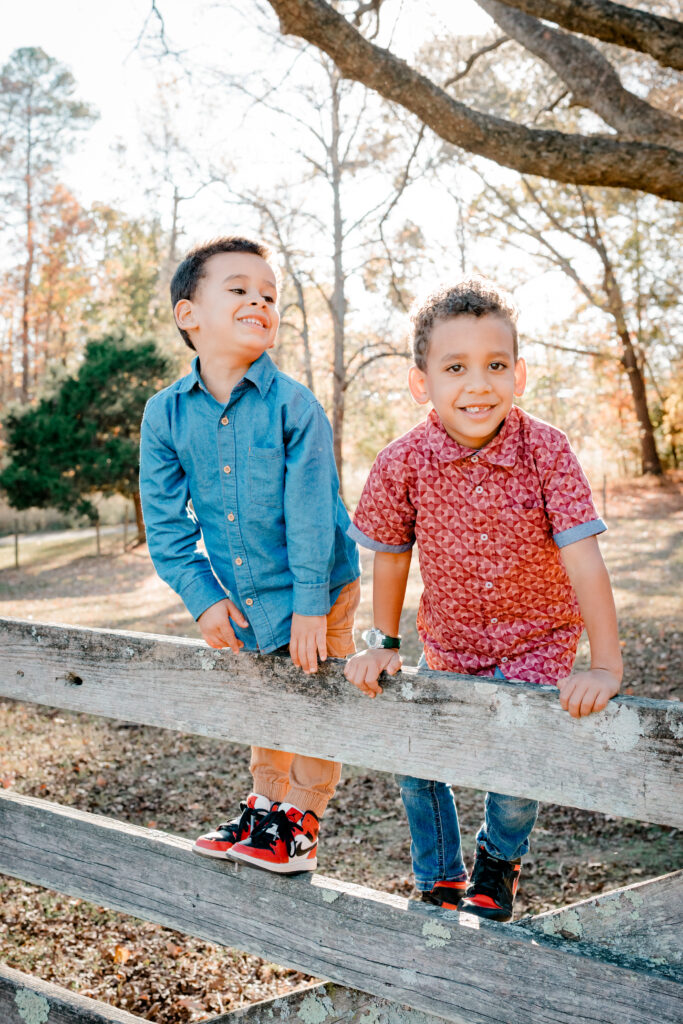 Boys standing on fence smiling at golden hour during Atlanta family photo session