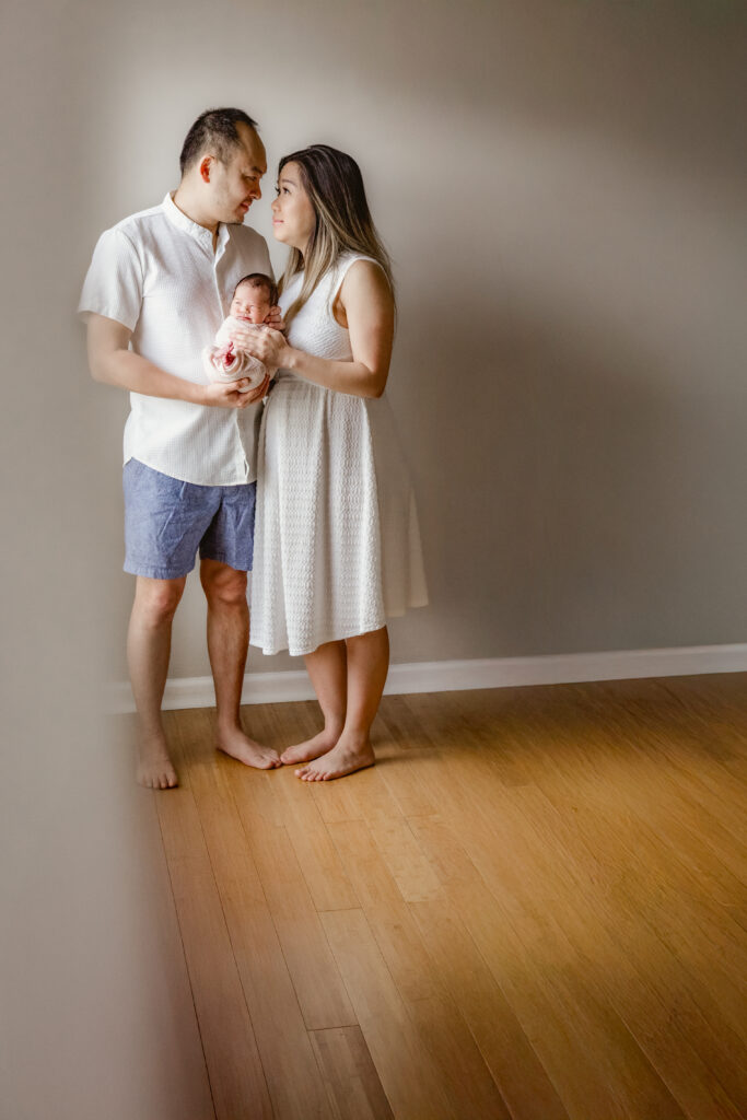 mom and dad hold newborn baby during in-home session