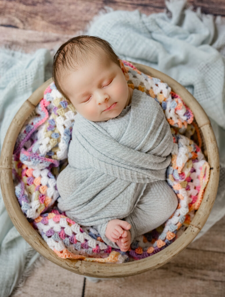 Baby nestled in colorful family heirloom blanket sleeping during his Tucker, Georgia newborn photography session. 