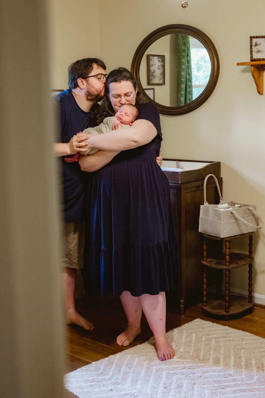 Newborn family snuggles baby in cheerful yellow nursery in Tucker, Georgia.