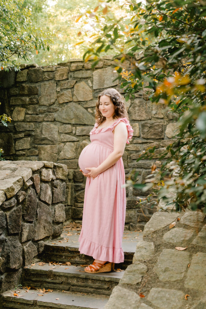 Expecting mom posting in pink dress on stone stairs in Stone Mountain, Georgia