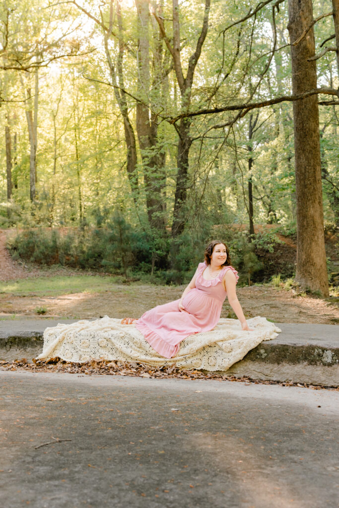 Mom in side lying position on rock with sun shining through during maternity session