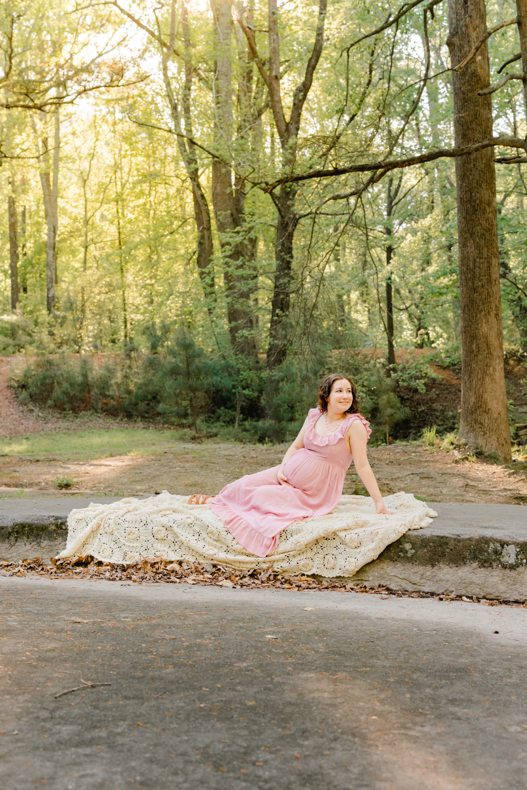 Mom in side lying position on rock with sun shining through during maternity session