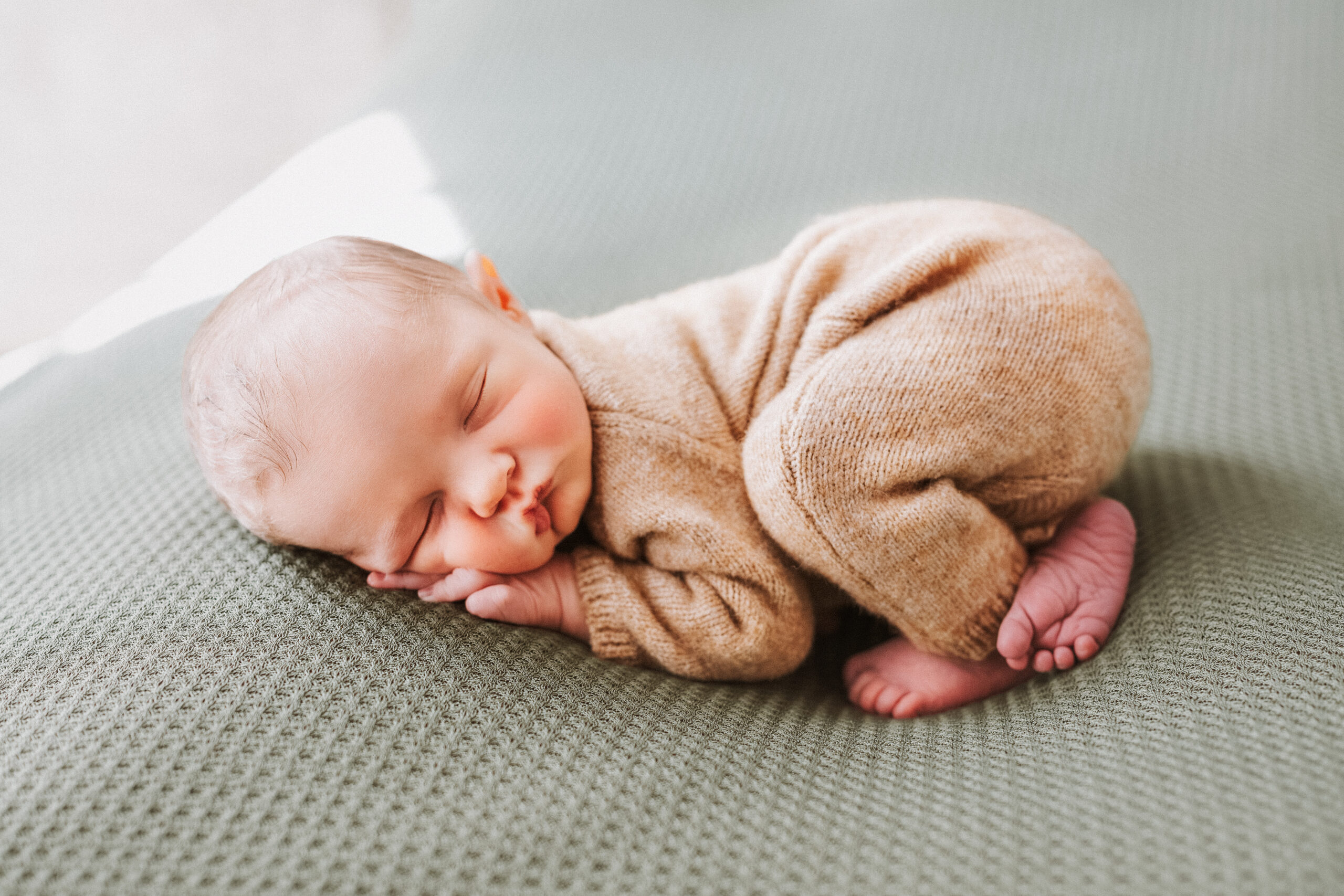 Newborn boy sleeping on his tummy on a green background